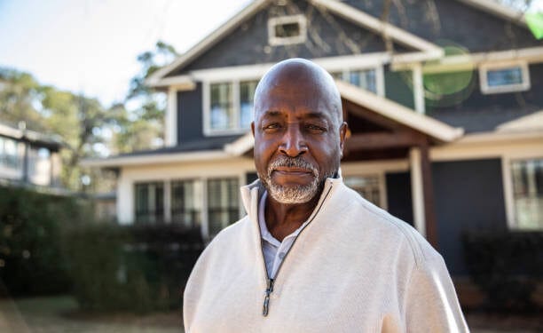 Portrait of senior man in front of his house