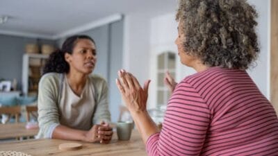 Sad woman refusing her friend's help during their conversation at home.