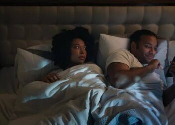 Man and wife in bed watching on phone
