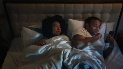 Man and wife in bed watching on phone