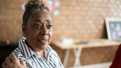Senior woman talking and crying in group therapy