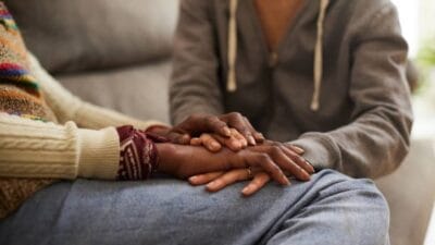 A woman with cancer and her daughter hand in hand.